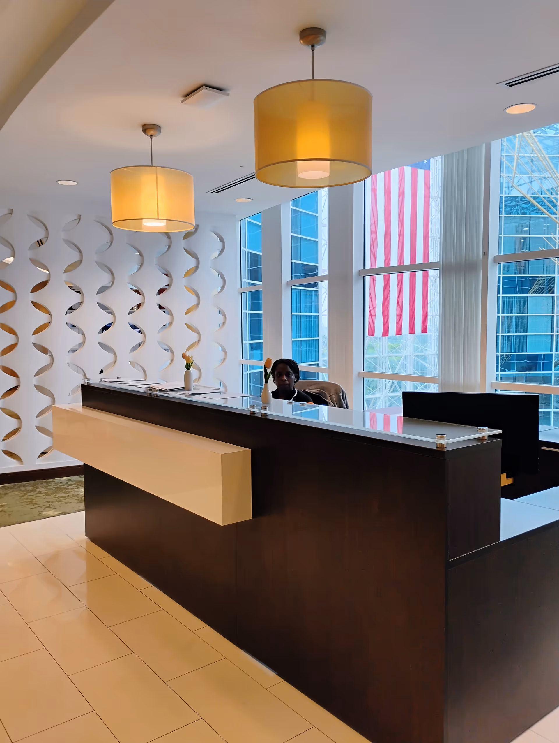 Modern office lobby with a dark reception desk and large windows.