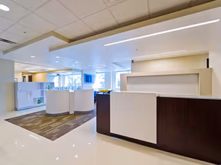 Modern senior living lobby with reception desk, curved seating, and bright lighting.