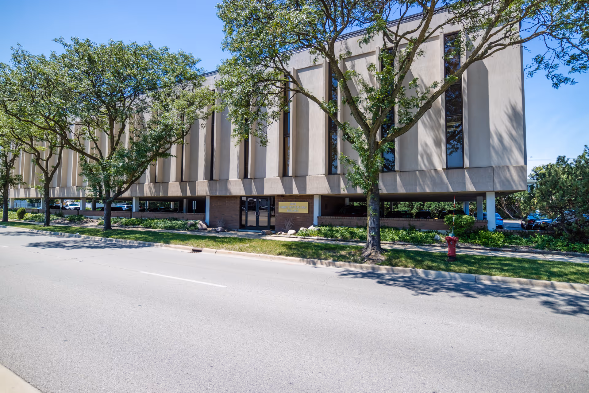 Exterior view of a large office-style building with trees and a street in front.
