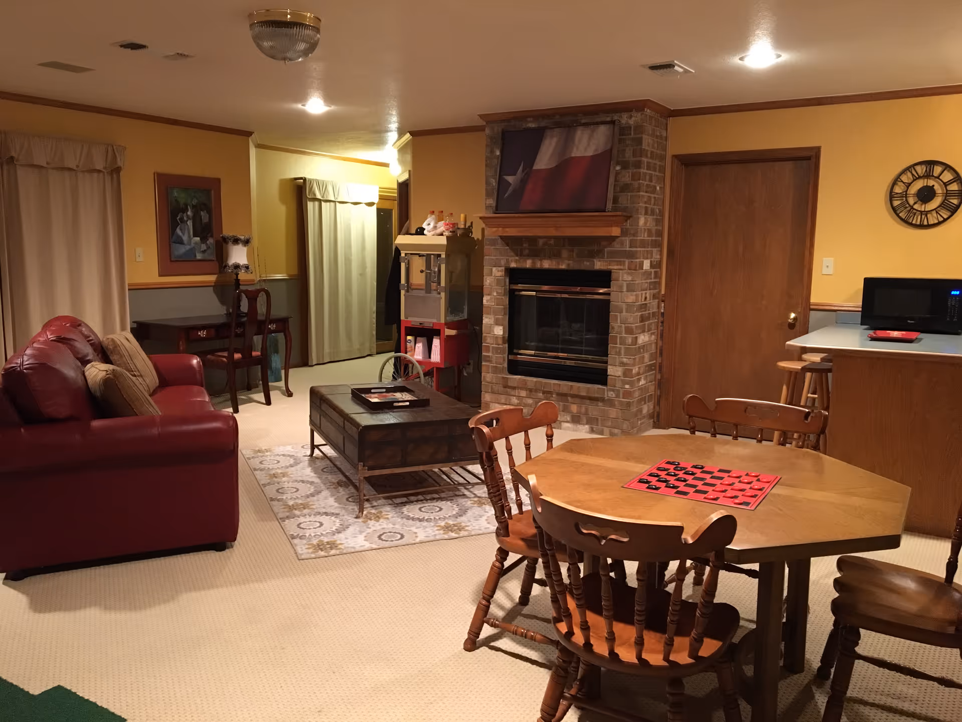 Cozy living area with sofa, fireplace, coffee table, and dining table in warm lighting.