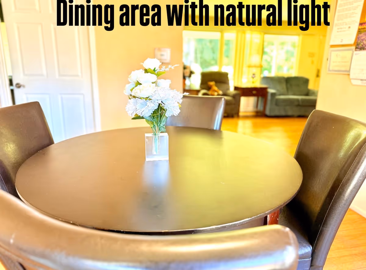 Round dining table with a vase of flowers in a bright dining area.