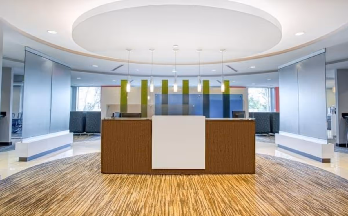 Bright lobby with circular ceiling lights, a reception desk, and colorful divider panels.