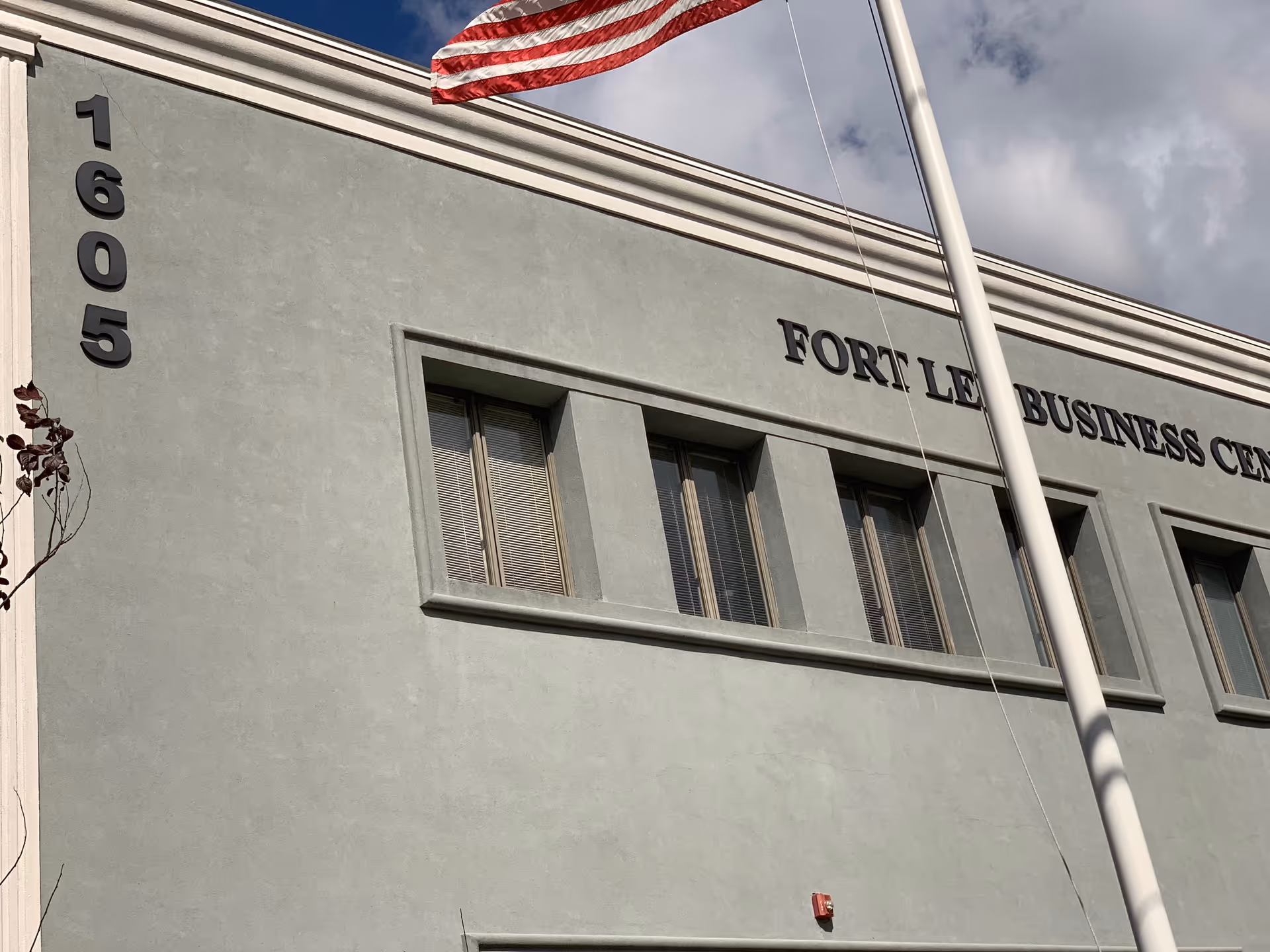 Exterior view of a grey building with an American flag and street address numbers.