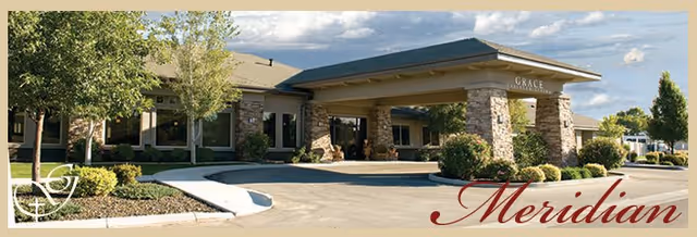 Exterior entrance of a senior living facility with stone columns and landscaped grounds.