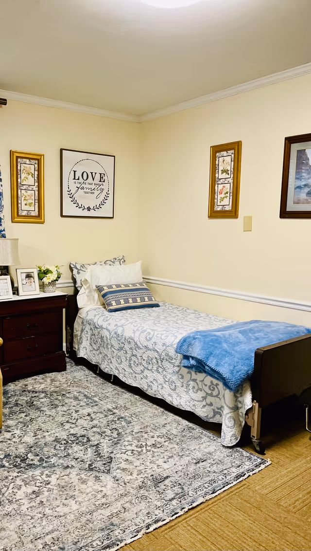 Single bed with patterned bedding and a blue throw in a neatly decorated room with a nightstand and framed wall art.