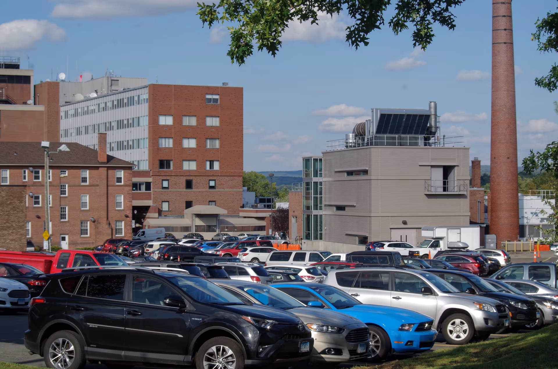 Exterior view of Middlesex Hospital buildings with a crowded parking lot and clear blue sky.