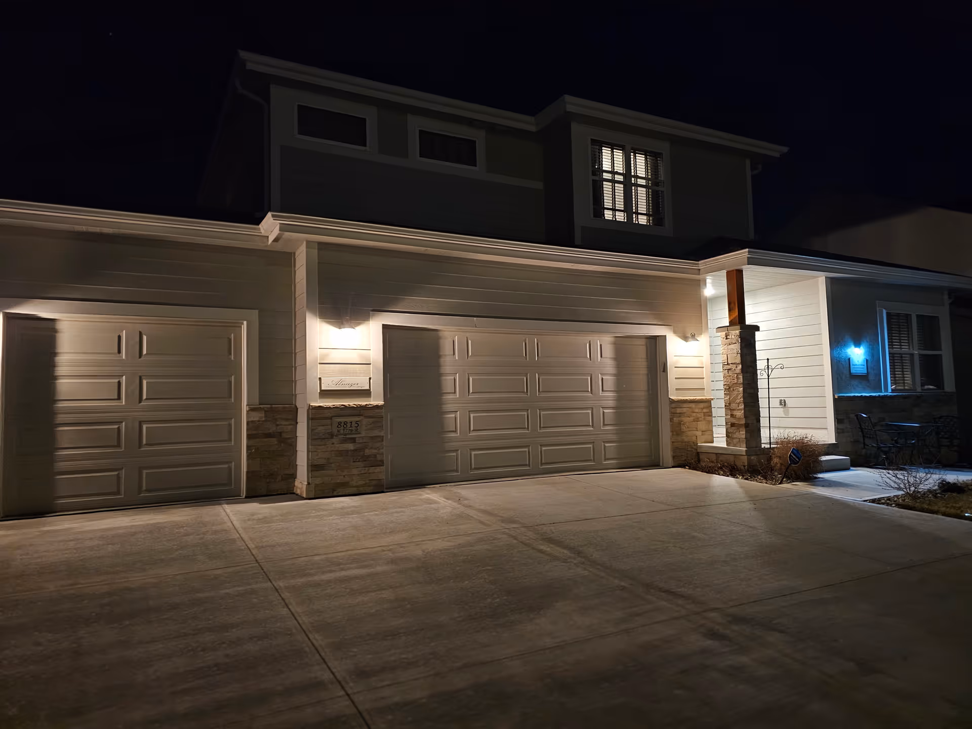 Night exterior of a senior living facility with three garage bays and lit entry.