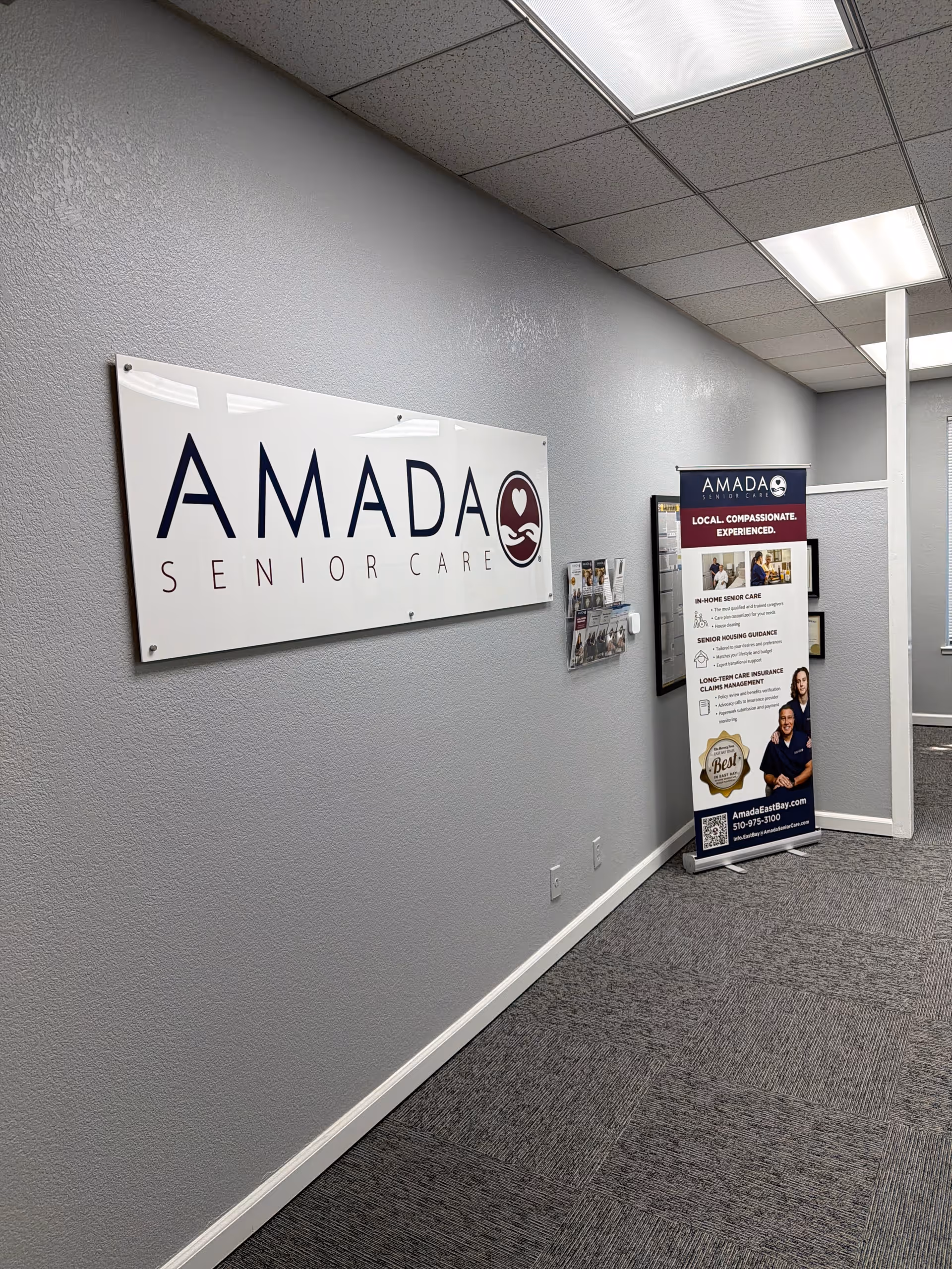 Interior corridor featuring Amada Senior Care sign and a brochure display near a doorway.