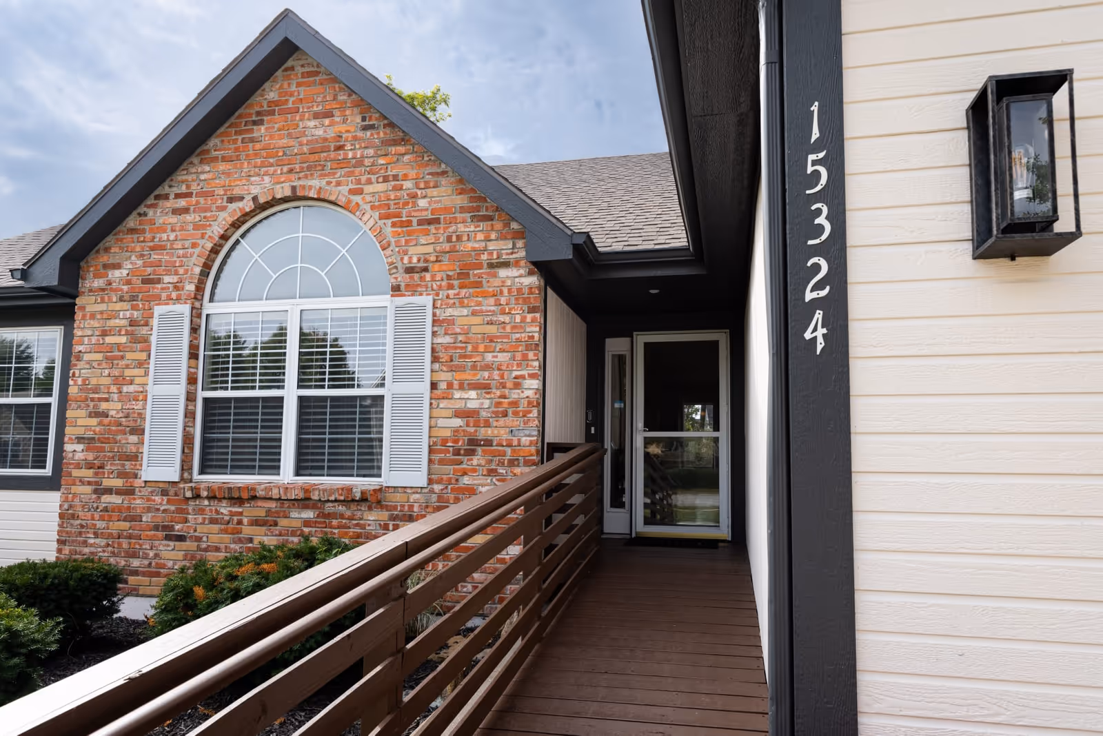 Front entrance of a brick senior living facility with a ramp and arched window.