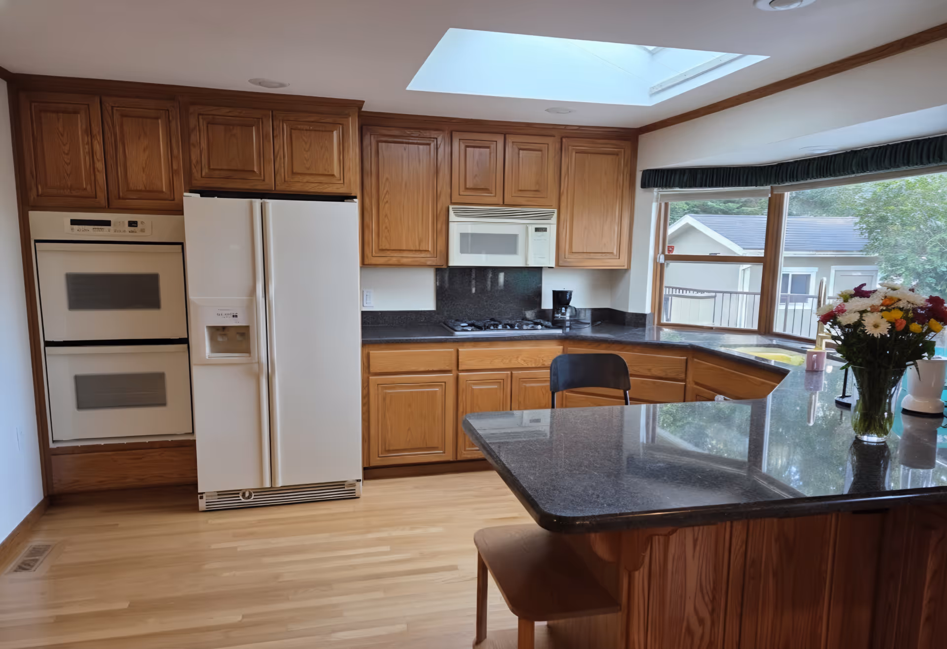 Bright kitchen with wooden cabinets, a central island, and a skylight.