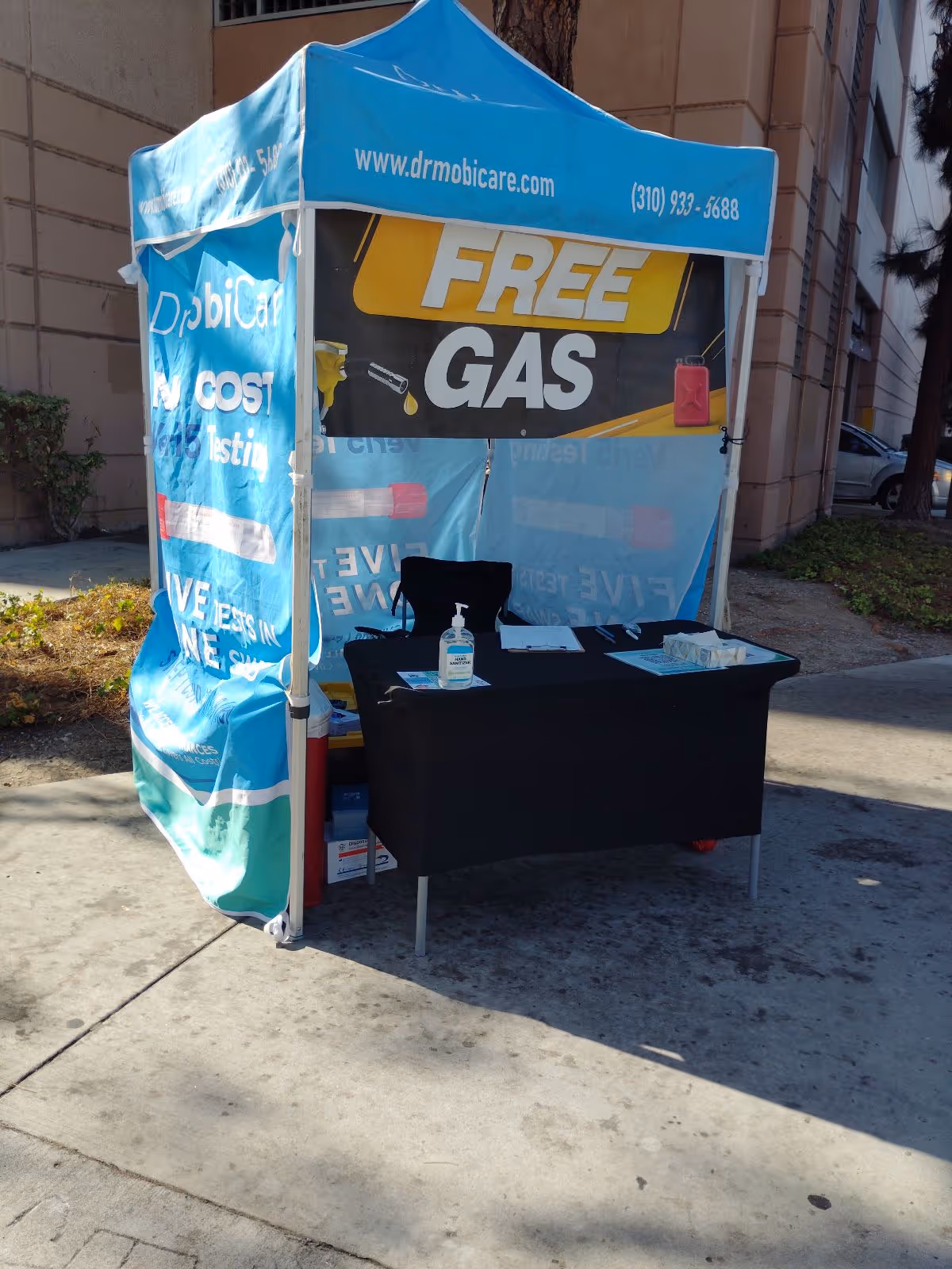Blue promotional tent with FREE GAS banner beside a black table outside.