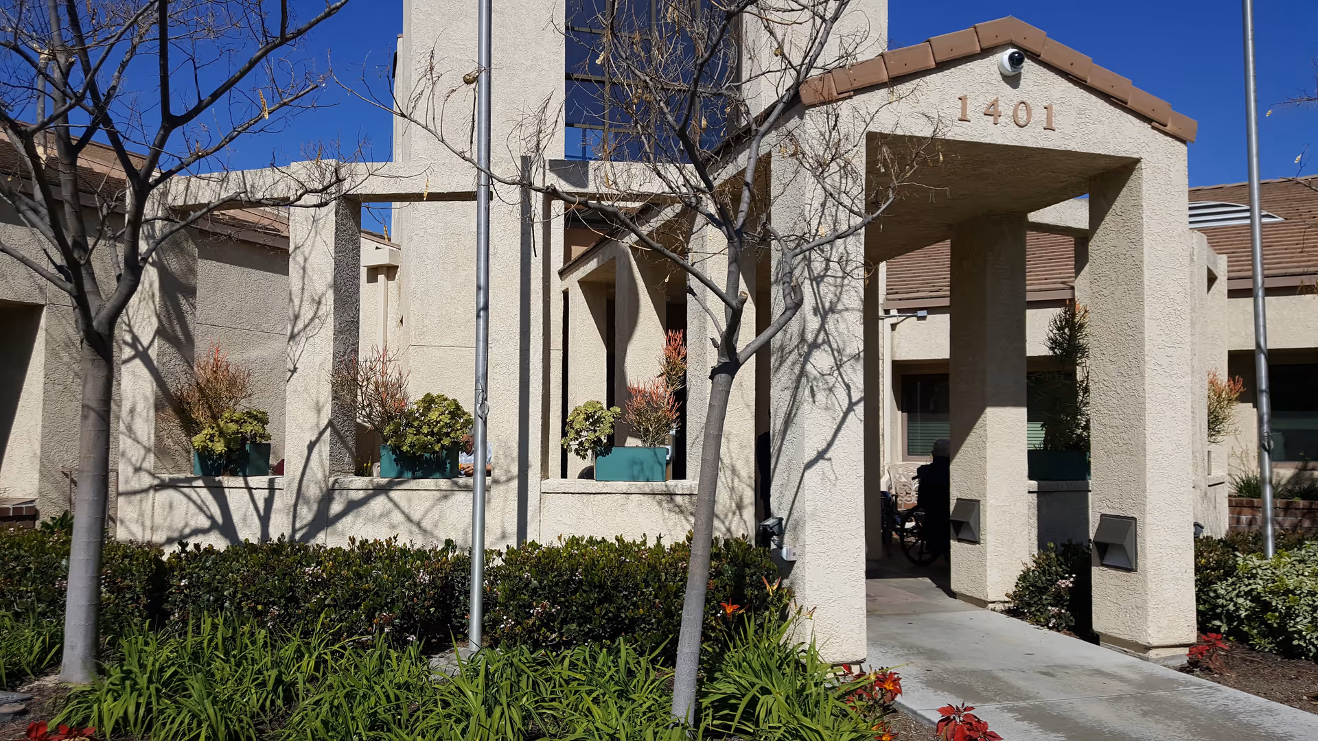 Exterior view of Walnut Village entrance with archway, walkway, and potted plants.