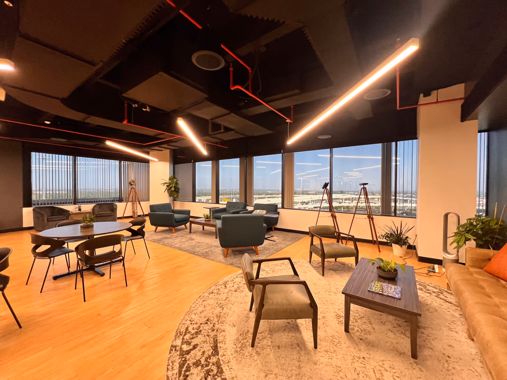 Spacious modern lounge with round tables, sofas, chairs, and large windows overlooking the city.