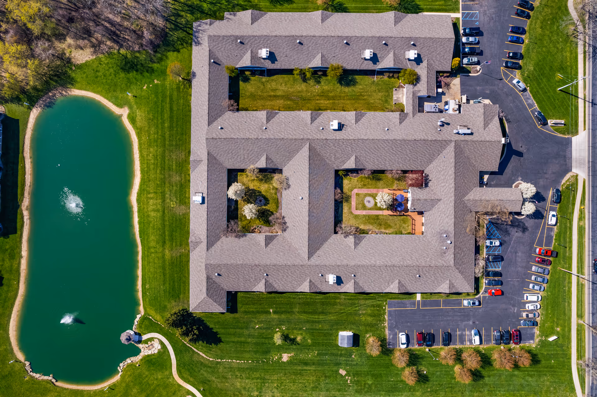 Aerial view of The Heritage Assisted Living Community building, courtyard, pond, and parking.