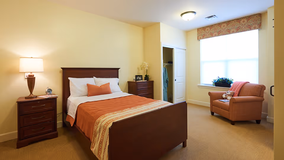 A bedroom with a wooden bed, two nightstands, a dresser, and a chair by the window.