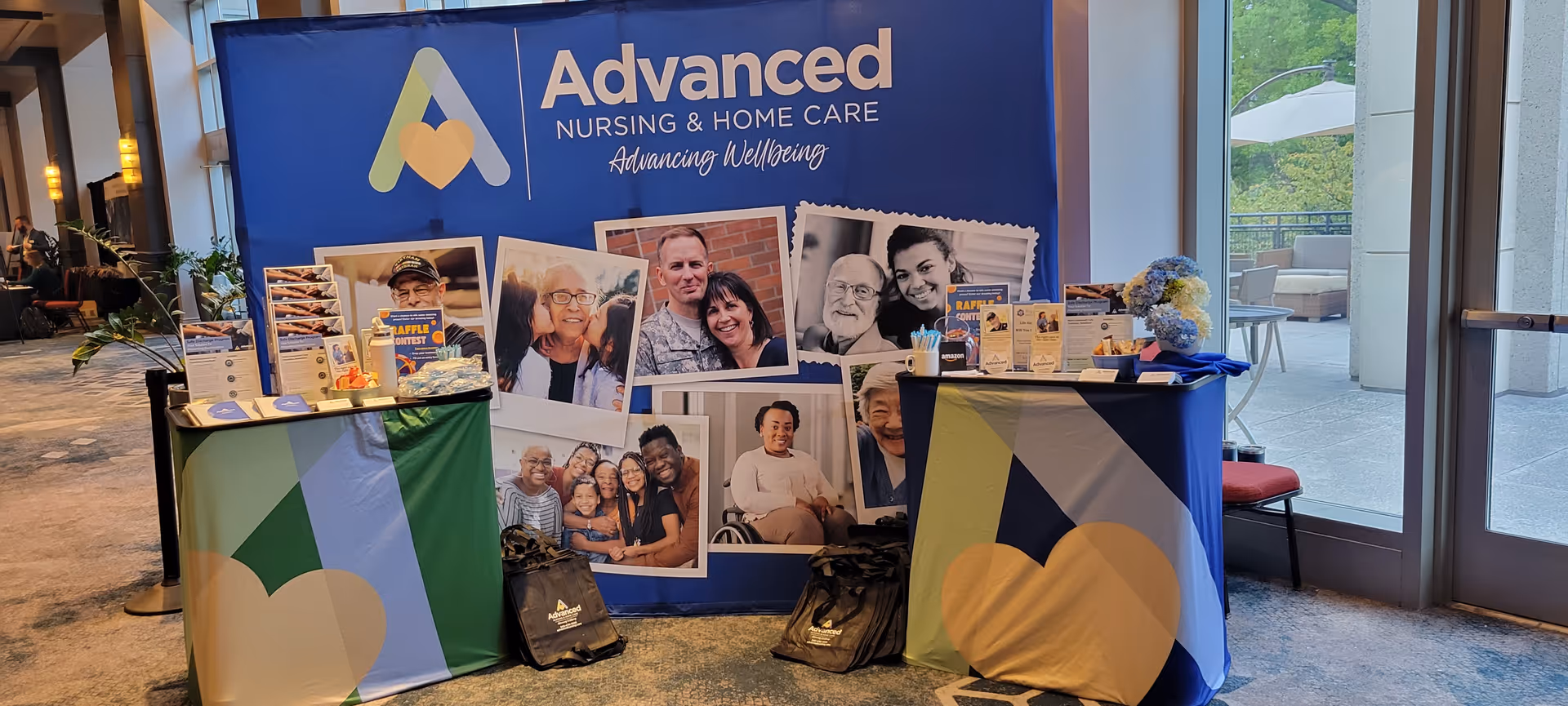 Promotional booth for Advanced Nursing & Home Care in a lobby with photos and brochures.