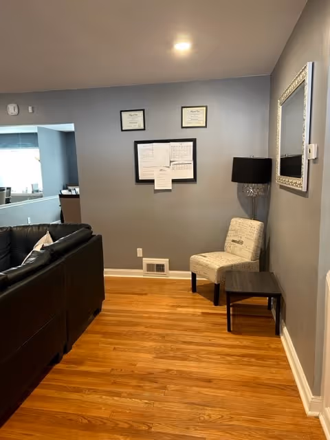 Cozy living room in a senior facility with sofa, chair, lamp, and wall art.
