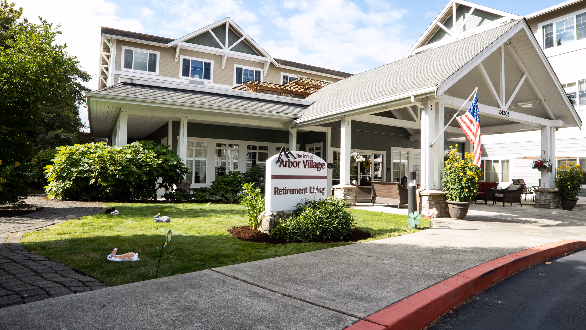 Front entrance of Arbor Village senior living facility with a covered porte-cochere, landscaping and a sign reading 'Arbor Village Retirement Living'.