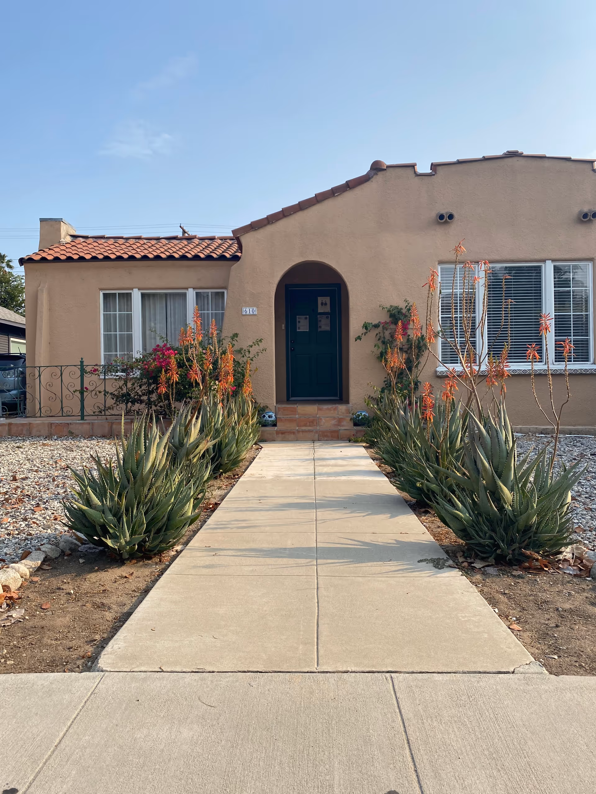 Pathway leads to a beige senior living building entrance with desert landscaping.