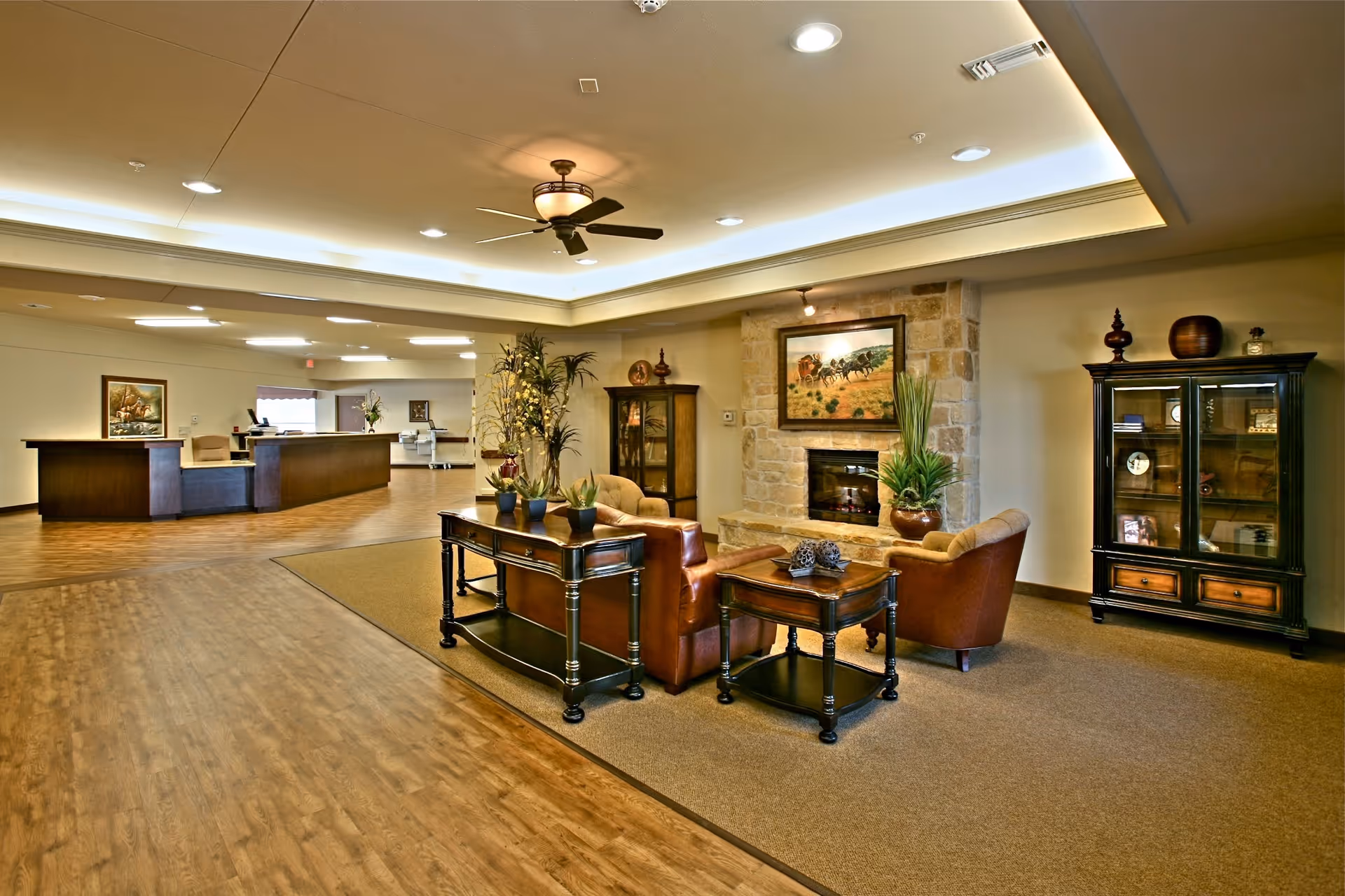 Spacious senior living lobby with fireplace, seating, and decorative cabinet.