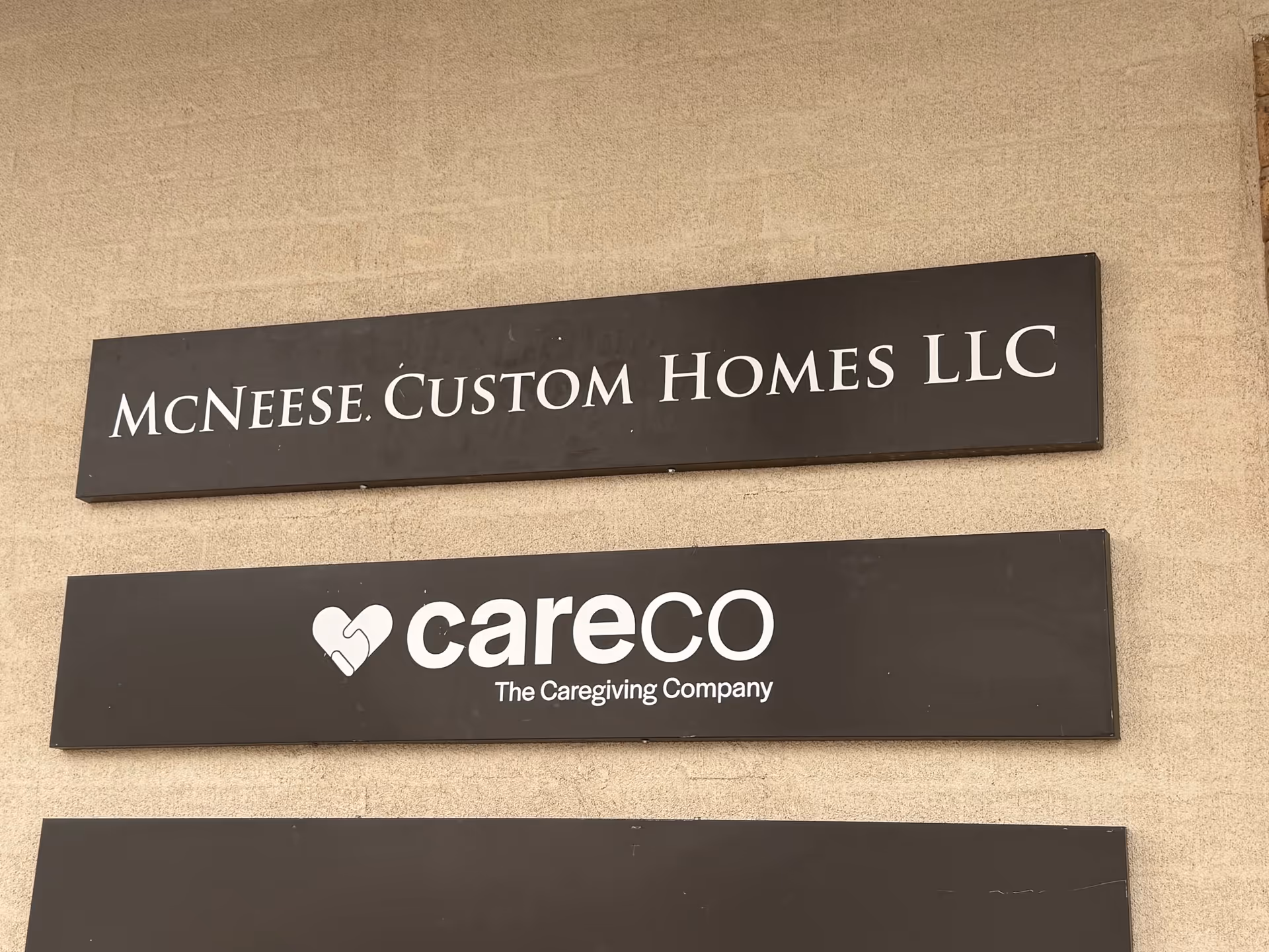 Exterior wall with MCNEESE CUSTOM HOMES LLC and CareCo Caregiving Company signs