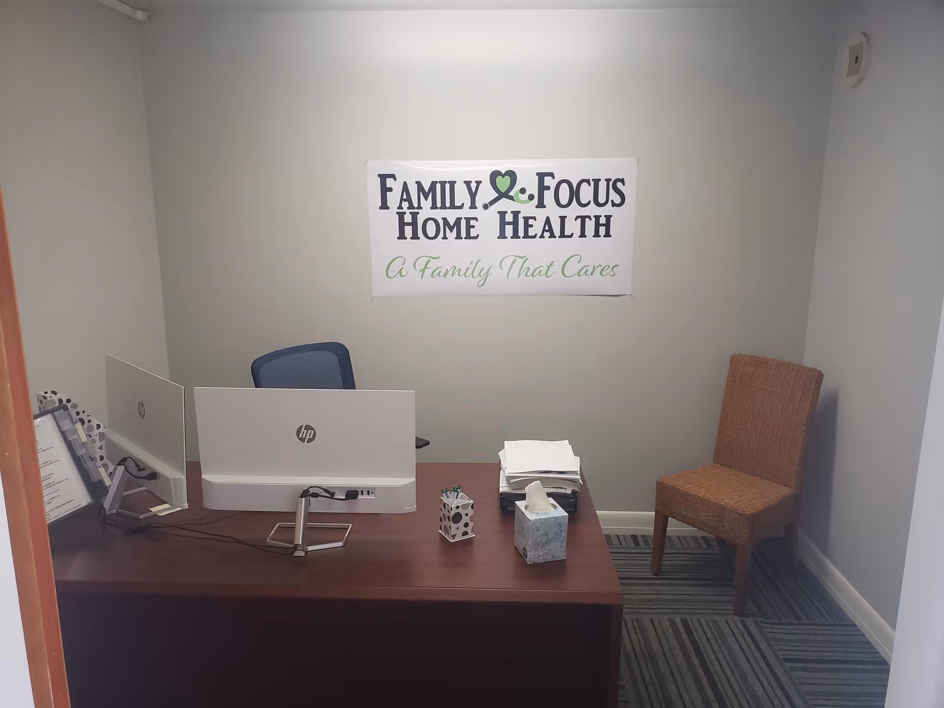 Reception desk with computer and a sign reading Family Focus Home Health, plus a chair.