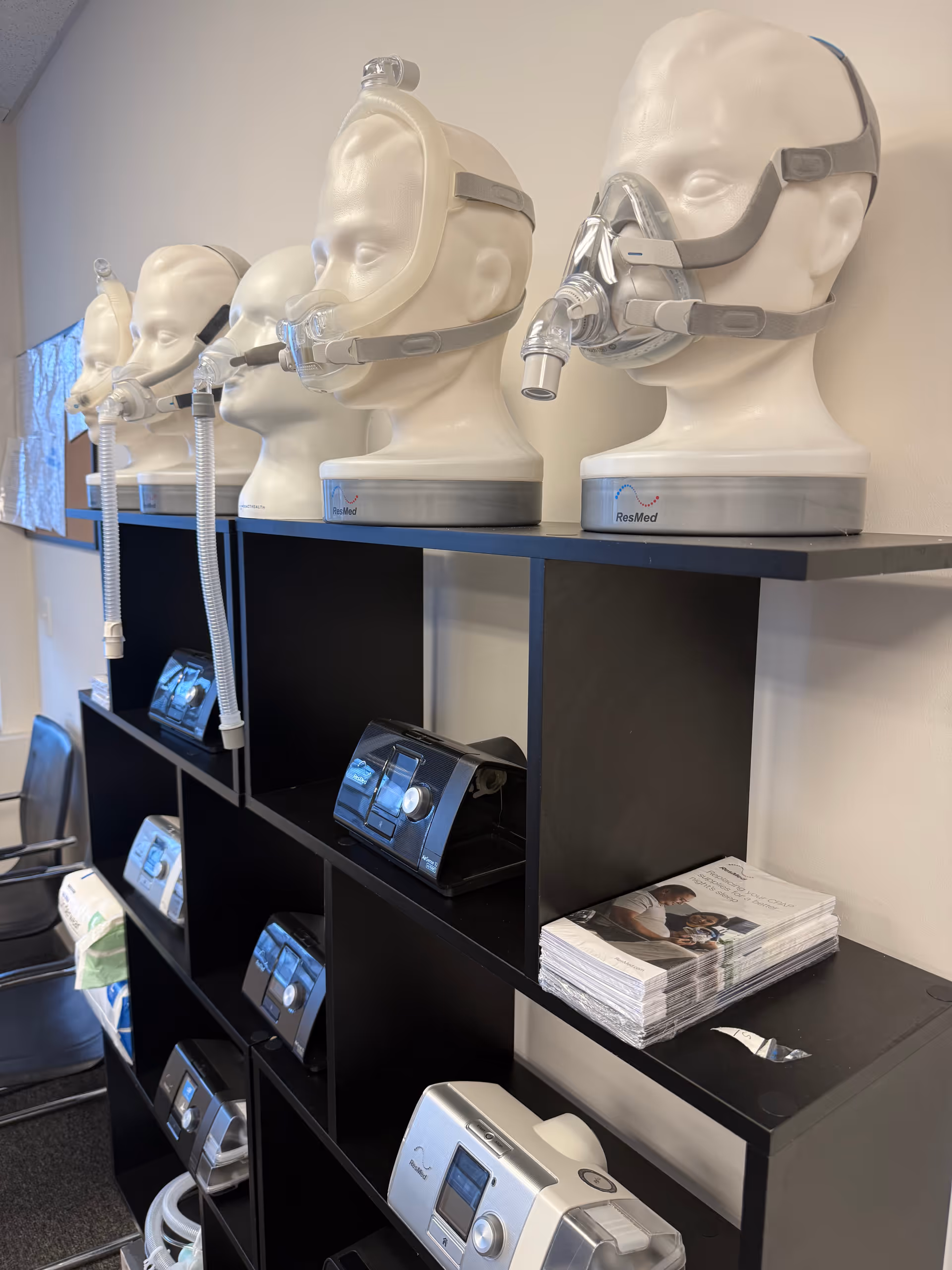 Mannequin heads wearing CPAP masks displayed on shelves with medical equipment