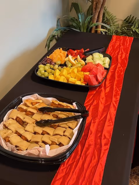 Fruit platter and pastry tray arranged on a table with a red runner