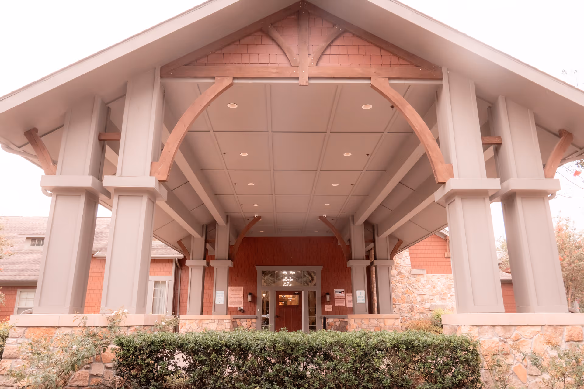 Covered porte-cochère with large wooden columns and beams at the building's front entrance.