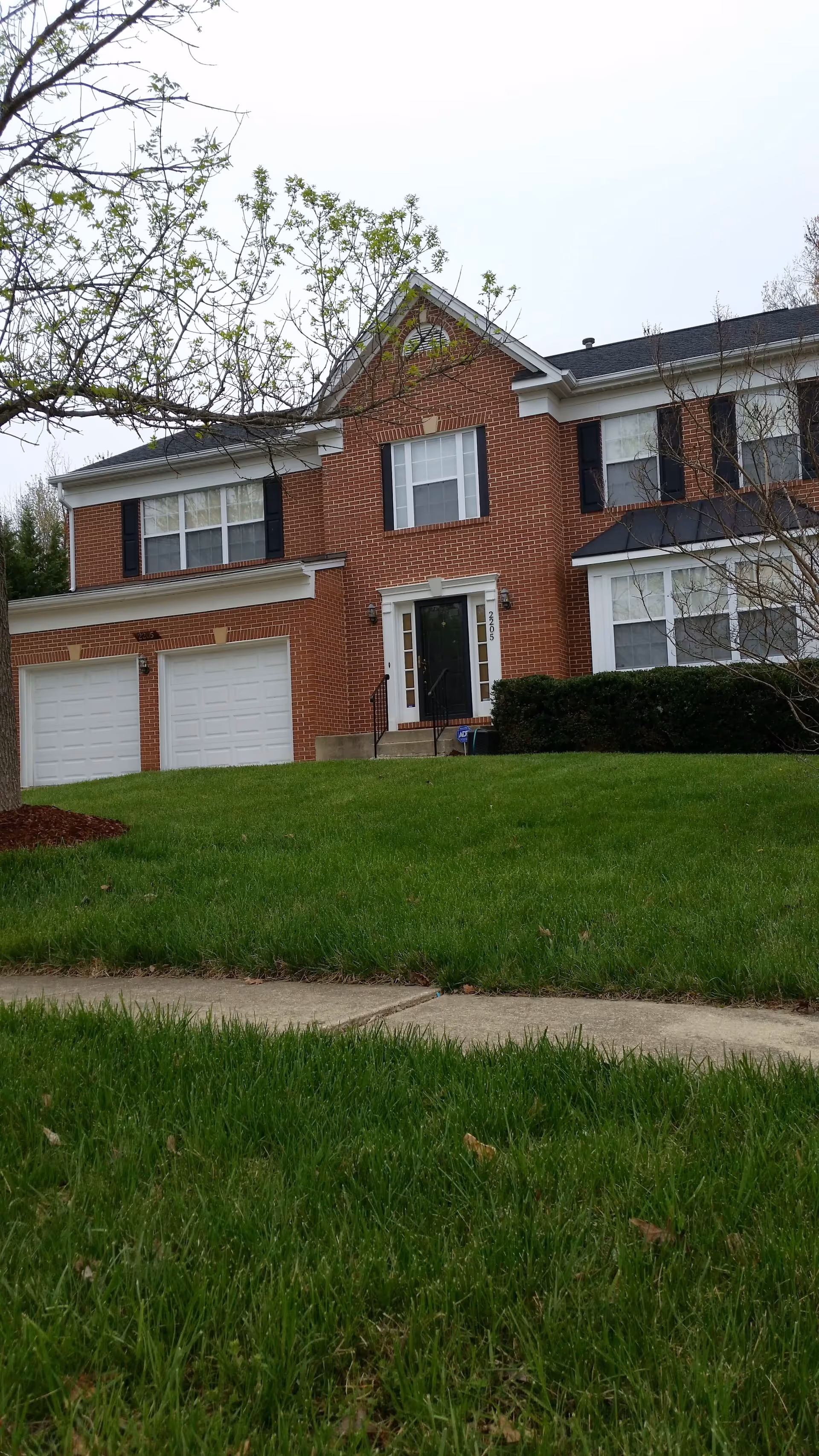 Two-story brick house with attached garage, front yard, and sidewalk