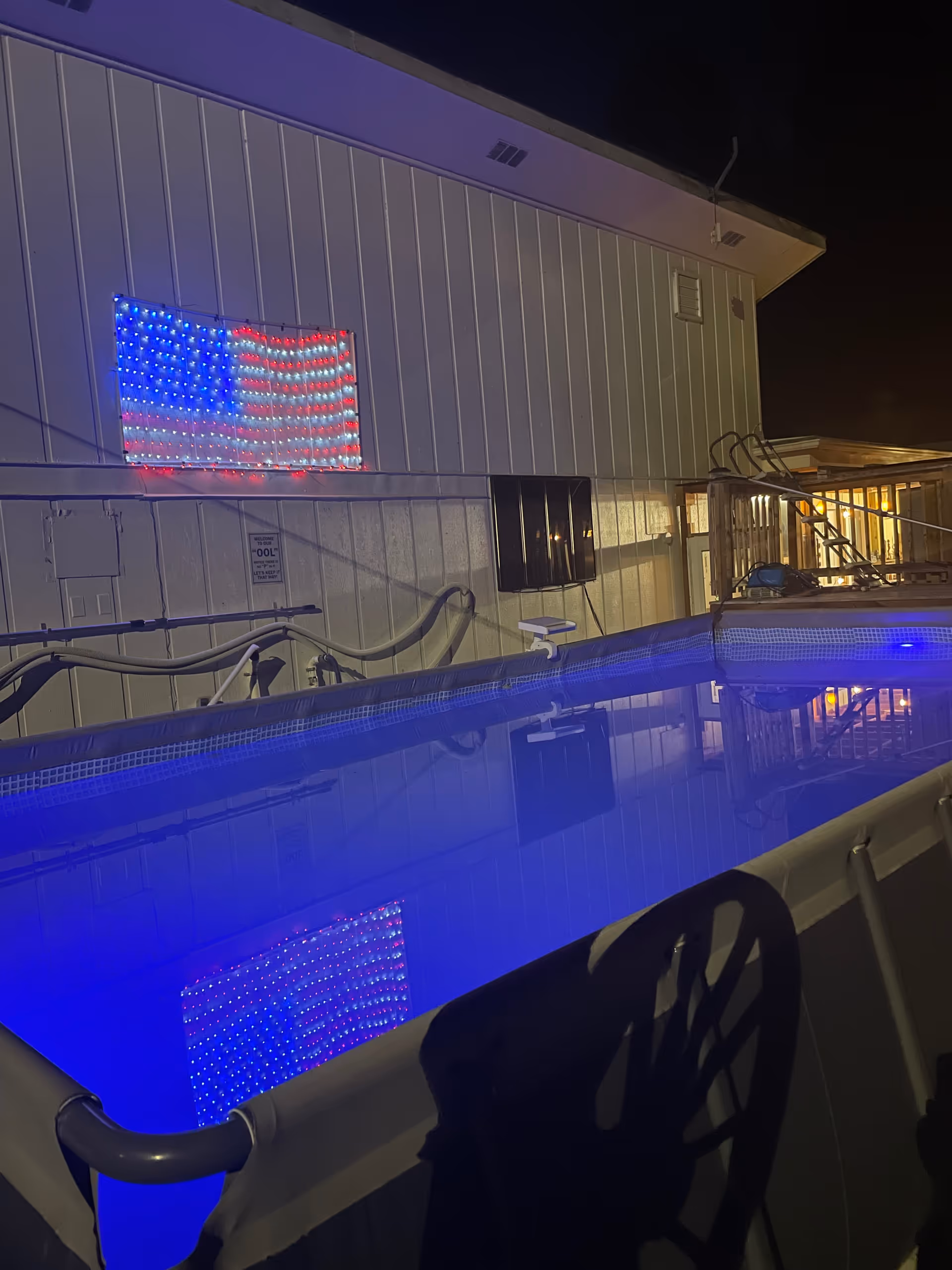 Night exterior of Collins Foster Care facility featuring a neon American flag and blue-lit pool.