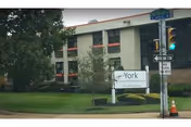 Exterior view of York Nursing and Rehabilitation Center with a lawn and street corner.