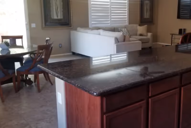 Open kitchen and living area with granite island, dark cabinets, and white sofa.