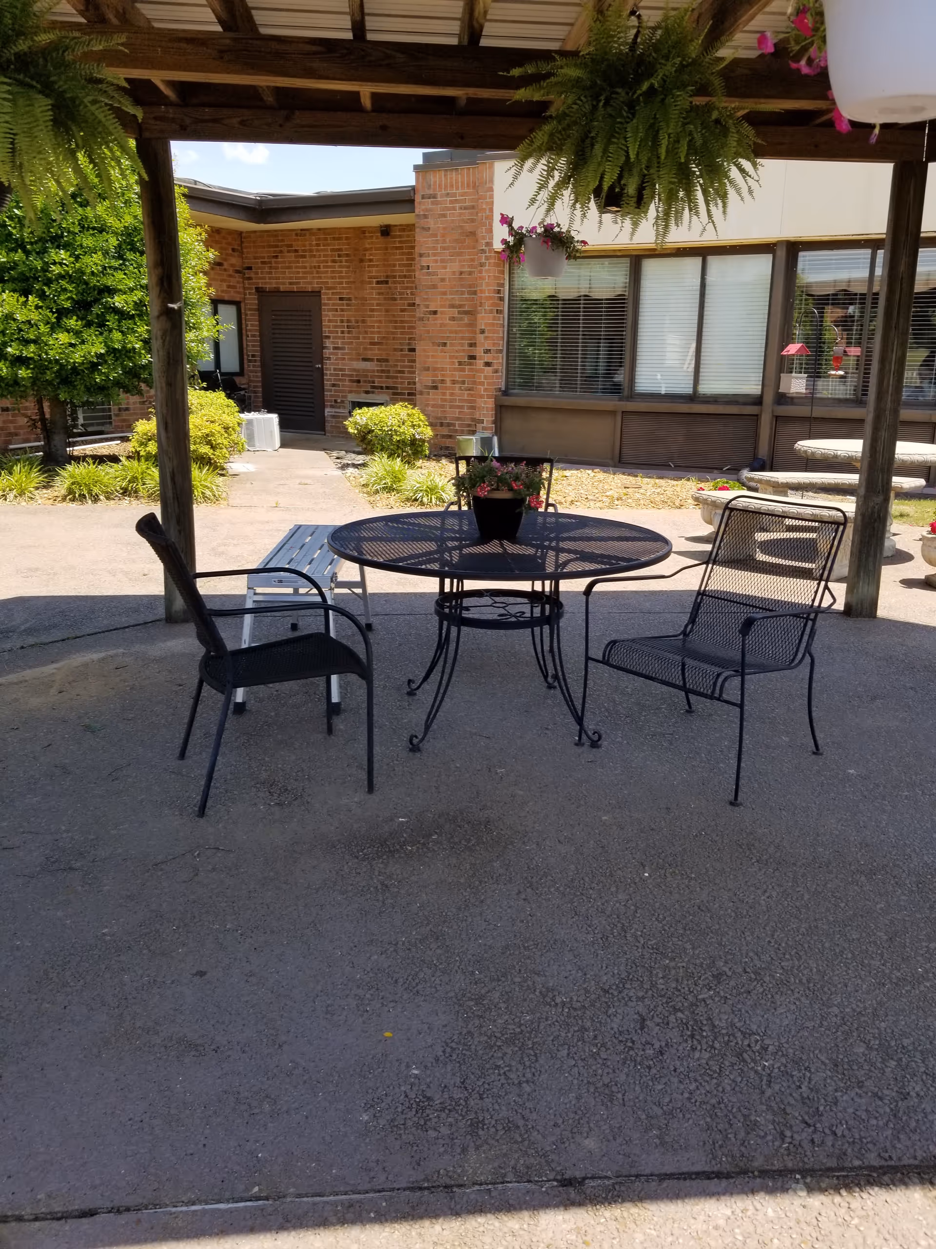 Outdoor patio with metal table and chairs under a wooden pergola at NHC Milan.