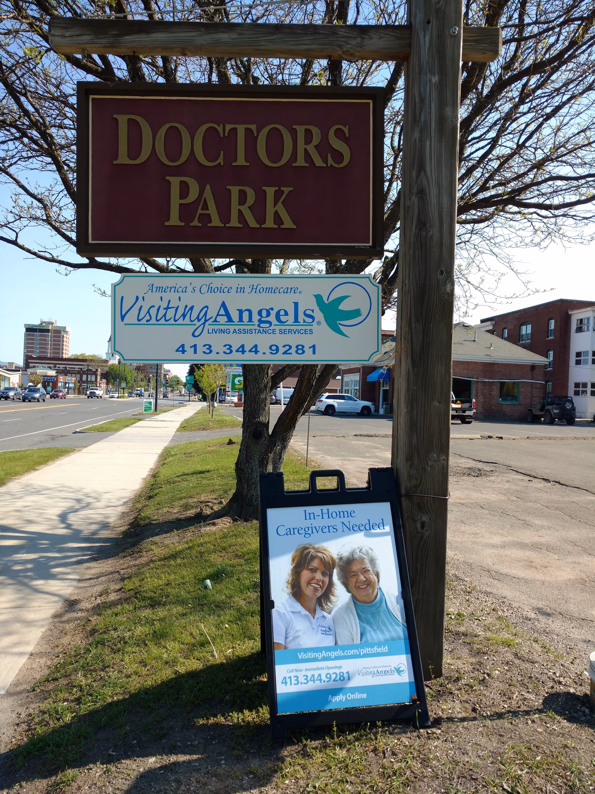 Outdoor street view with Visiting Angels sign and Doctors Park sign near sidewalk