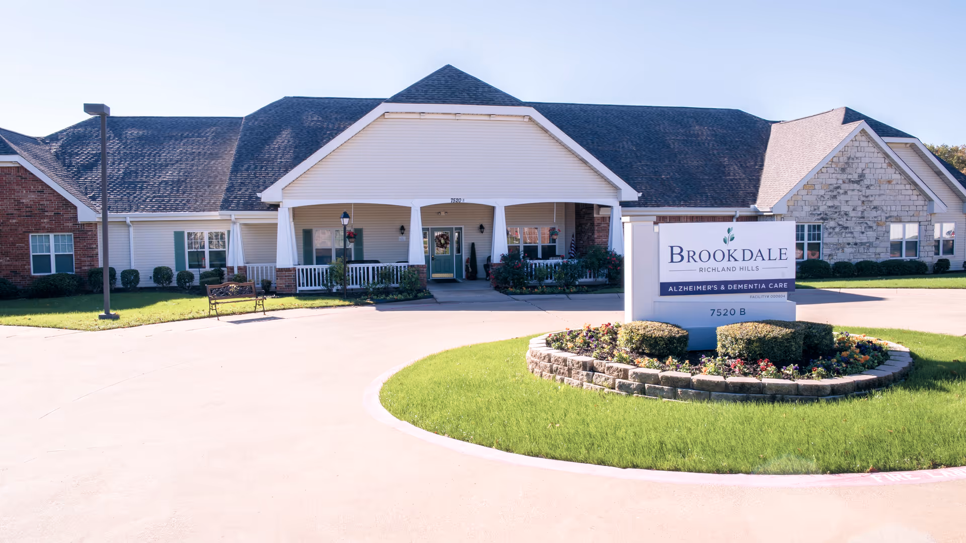 Exterior view of Brookdale Richland Hills facility with entrance, sign, and circular landscaping.