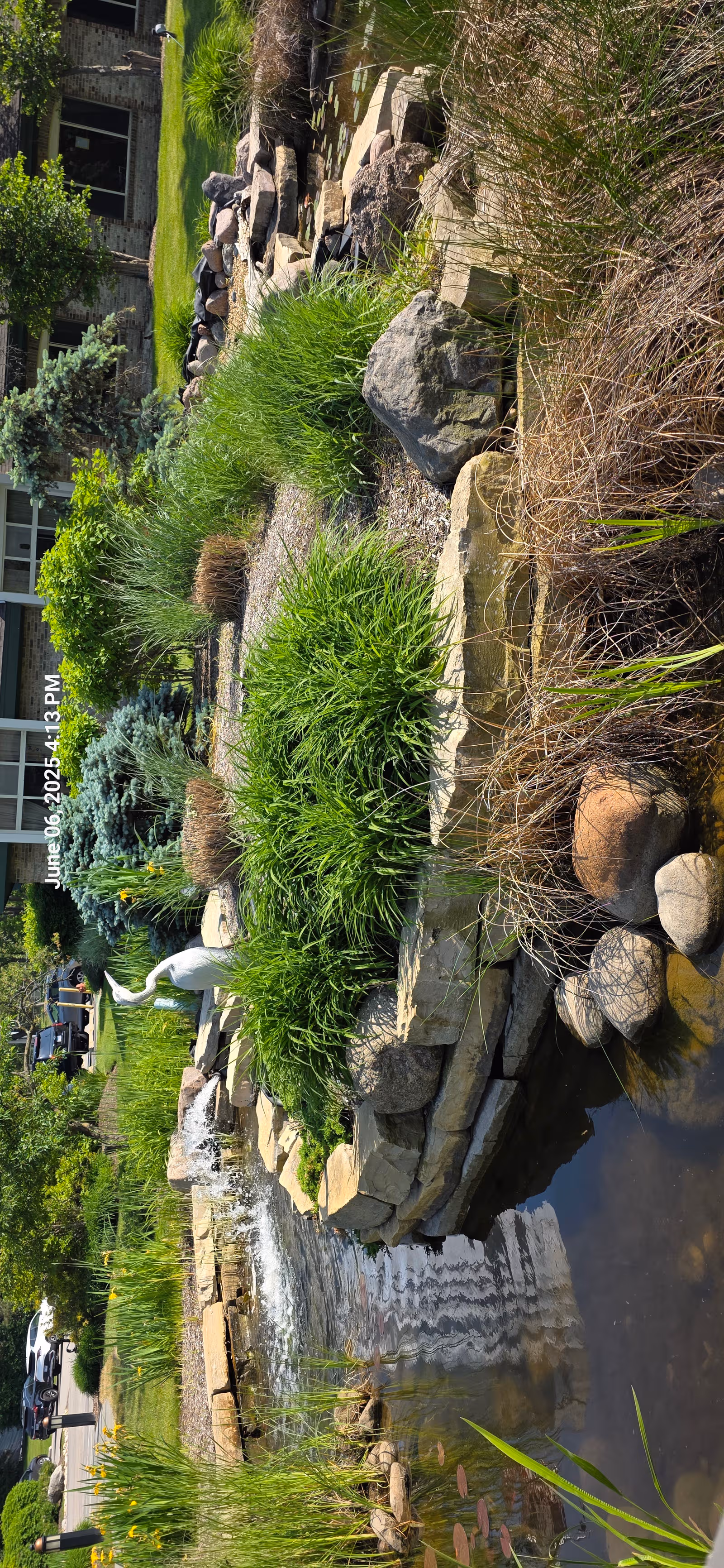 Exterior view of Alden Estates of Barrington featuring a landscaped rock garden with a waterfall.