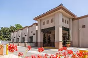 Exterior view of Main Place Post Acute building with beige stucco walls and red flowers.