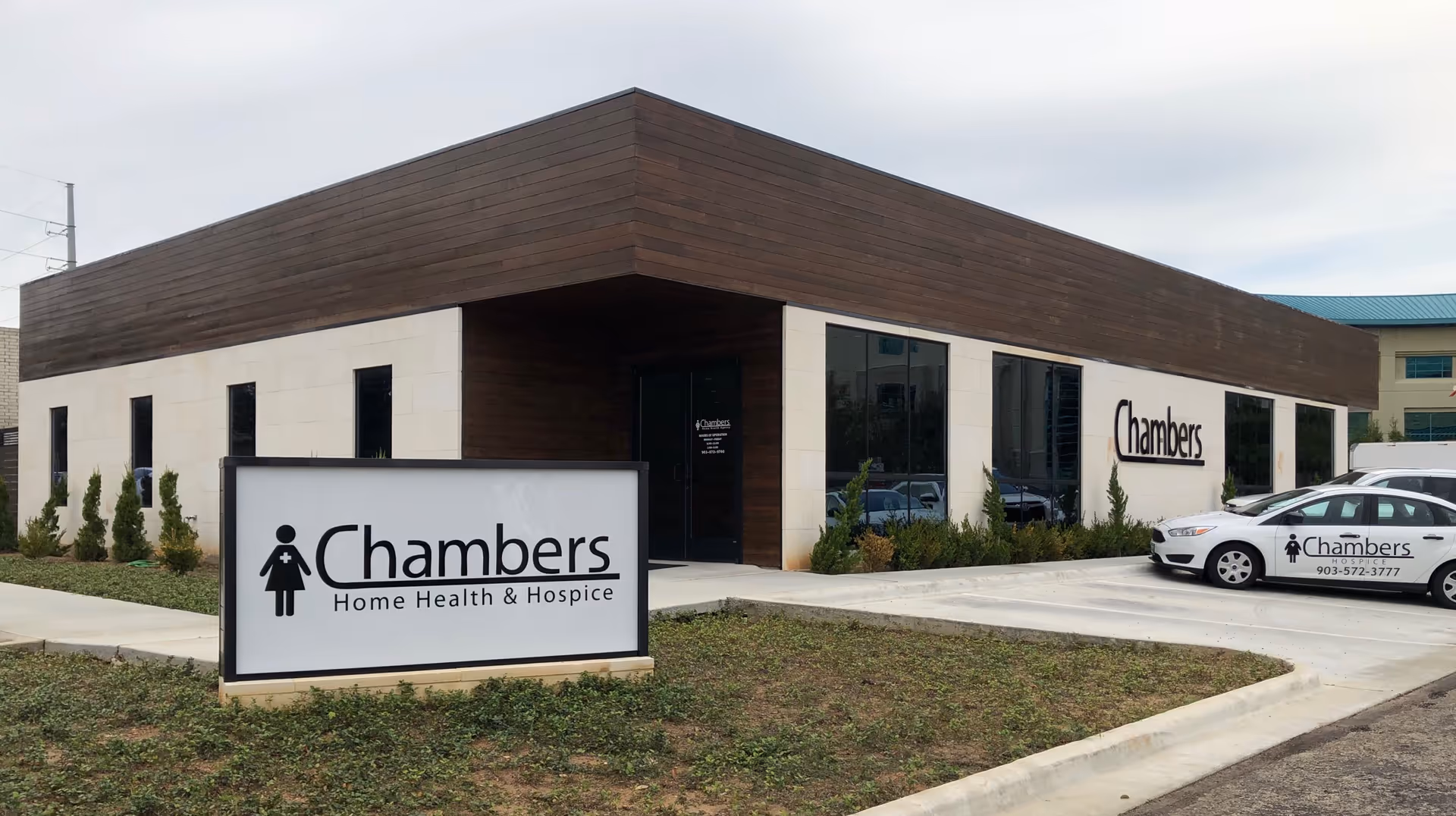 Modern single-story facility exterior with Chambers Home Health & Hospice signage and vehicles.
