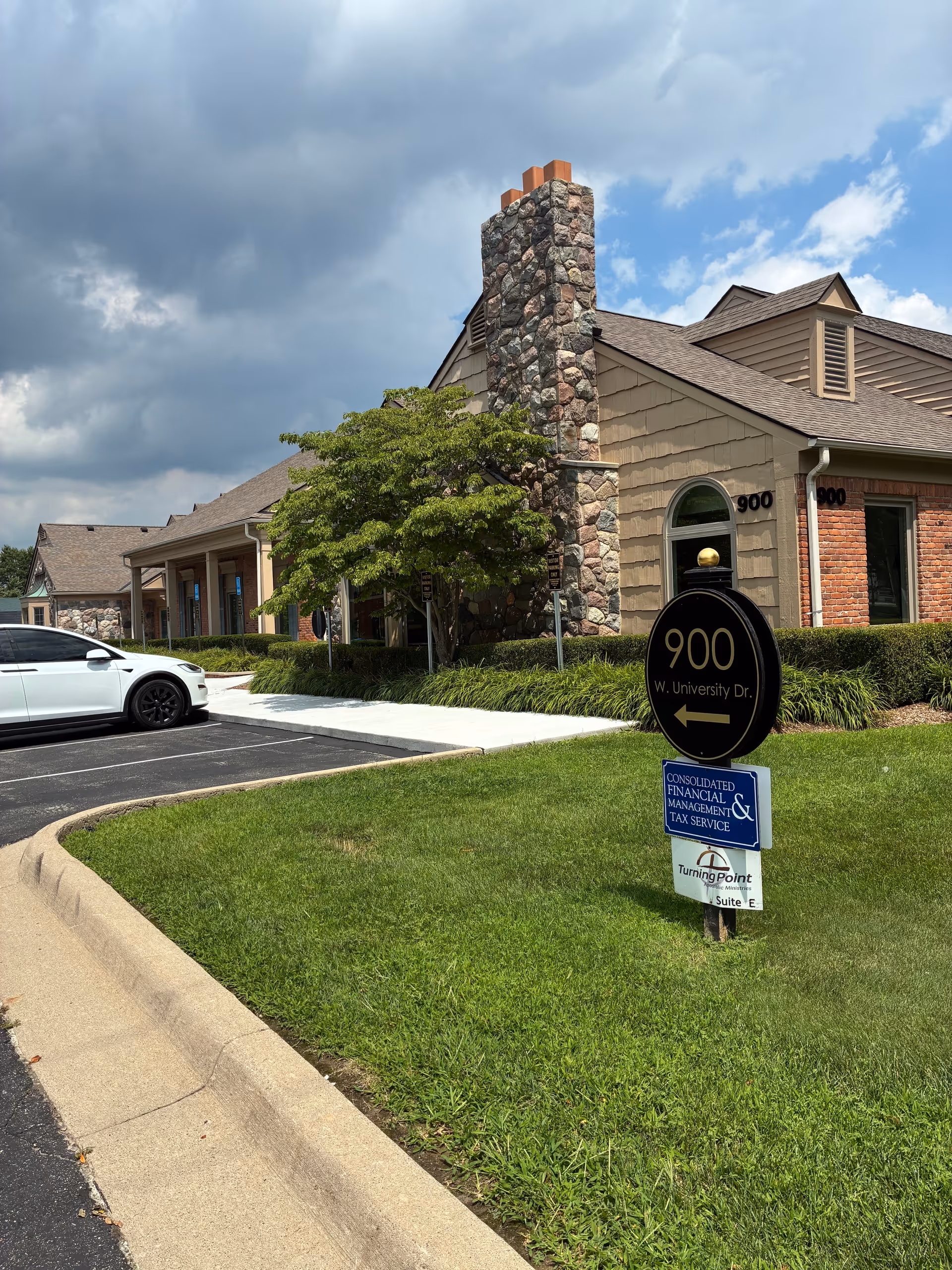 Exterior view of Hearthstone Hospice building with stone chimney, greenery, and a parking area.