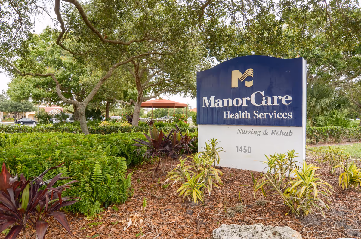 Exterior view of ManorCare Health Services Venice sign amid trees and landscaping