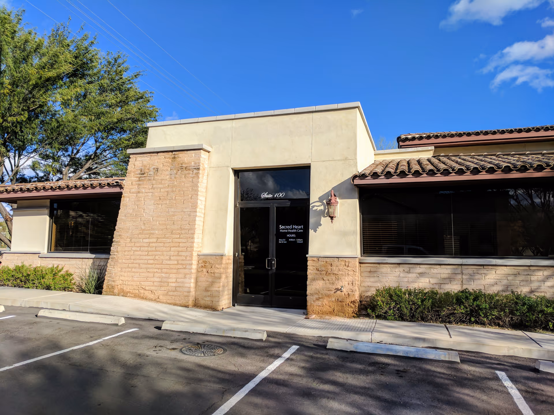 Exterior view of Sacred Heart Home Health Care entrance with glass doors and beige walls.