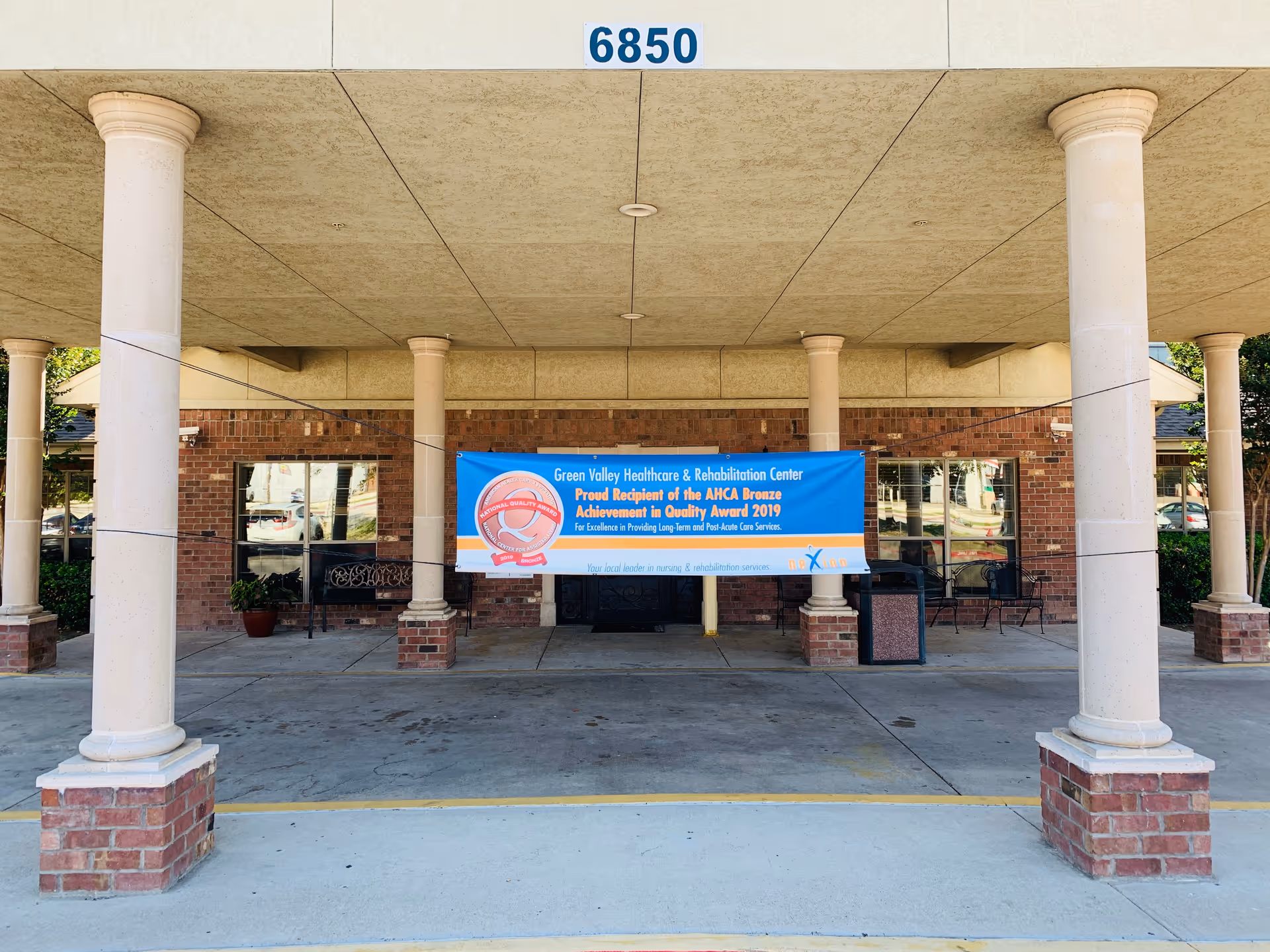 Exterior view of a brick facility with a blue banner hanging between columns