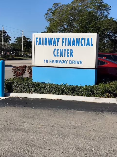 Exterior view of a blue and white Fairway Financial Center sign in a parking lot.
