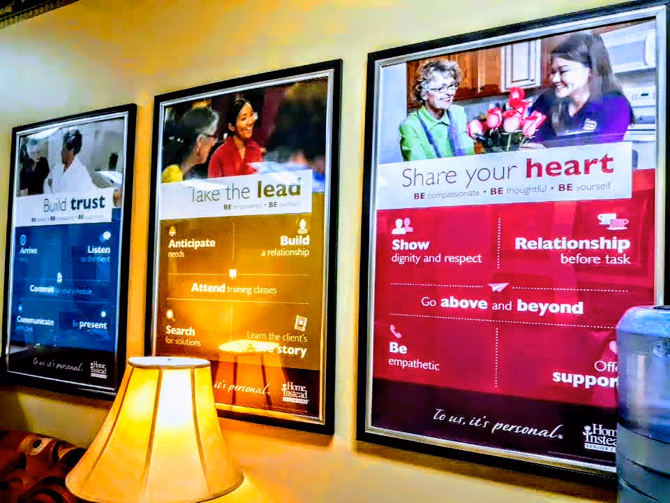 Interior wall with three framed posters and a lamp in the foreground.