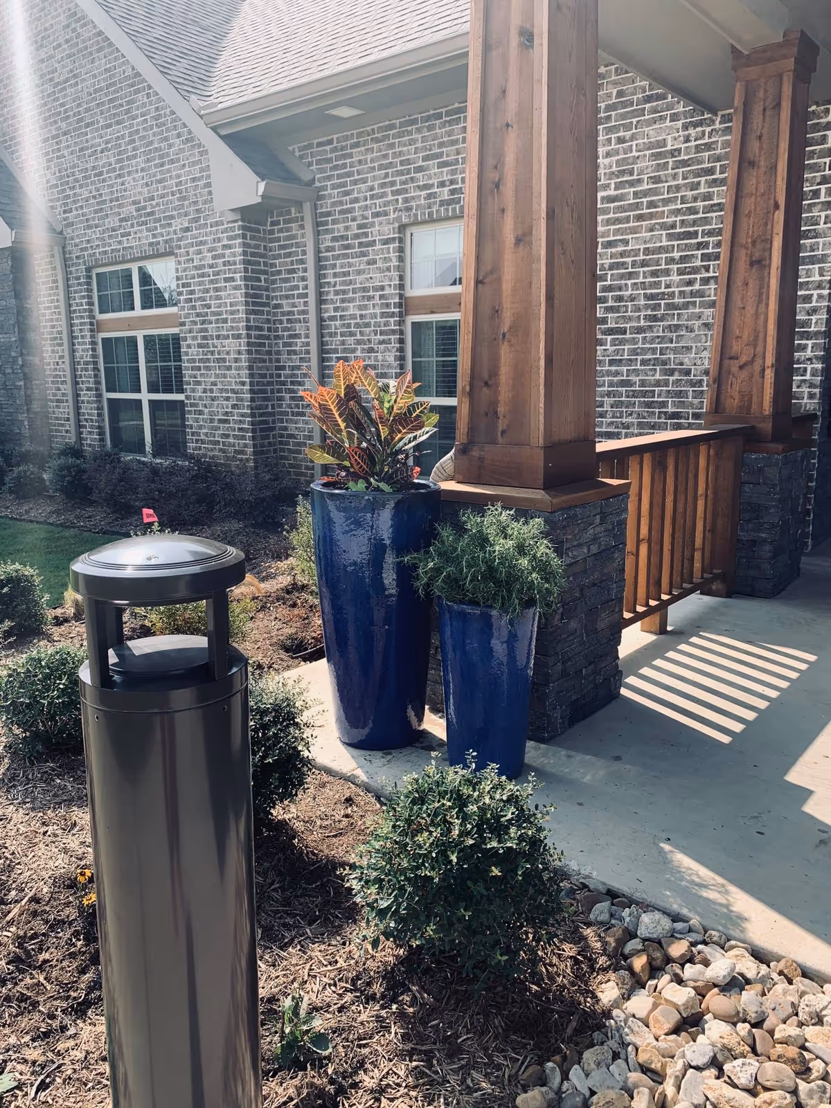 Front exterior of Teresa's House Assisted Living with brick walls, wooden posts, and blue planters.