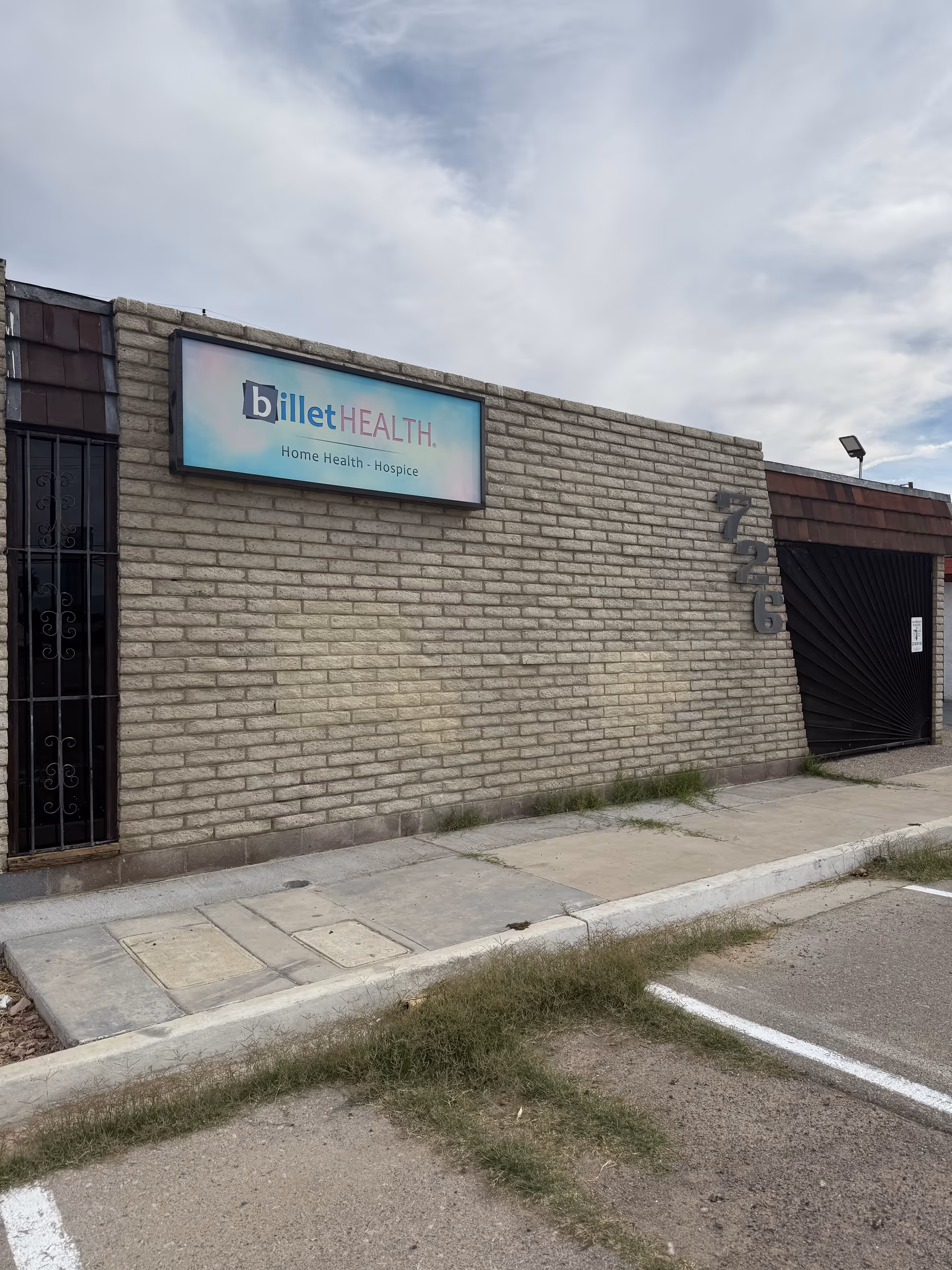 Brick exterior wall with Billet Health sign and black gate entrance.