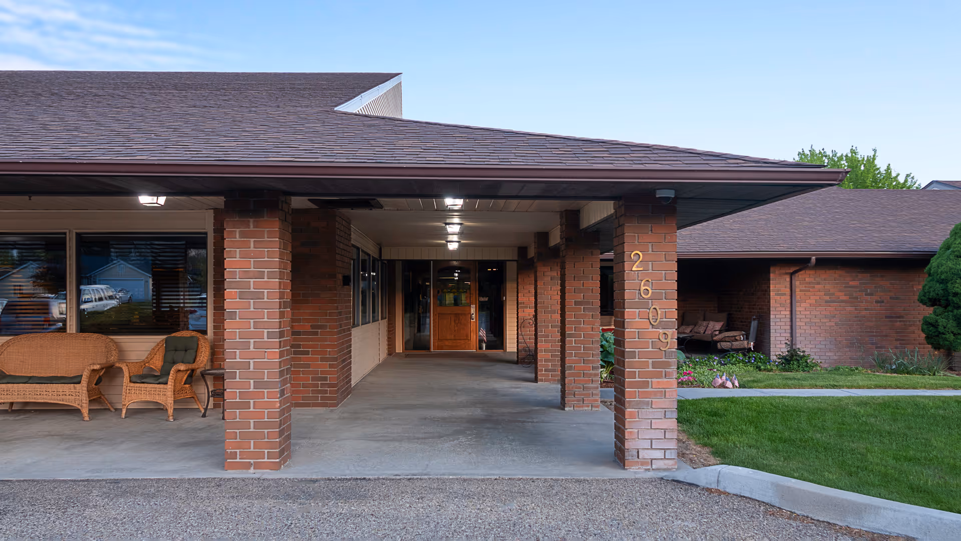 Sunny Ridge entrance with brick columns, covered walkway, and outdoor seating.