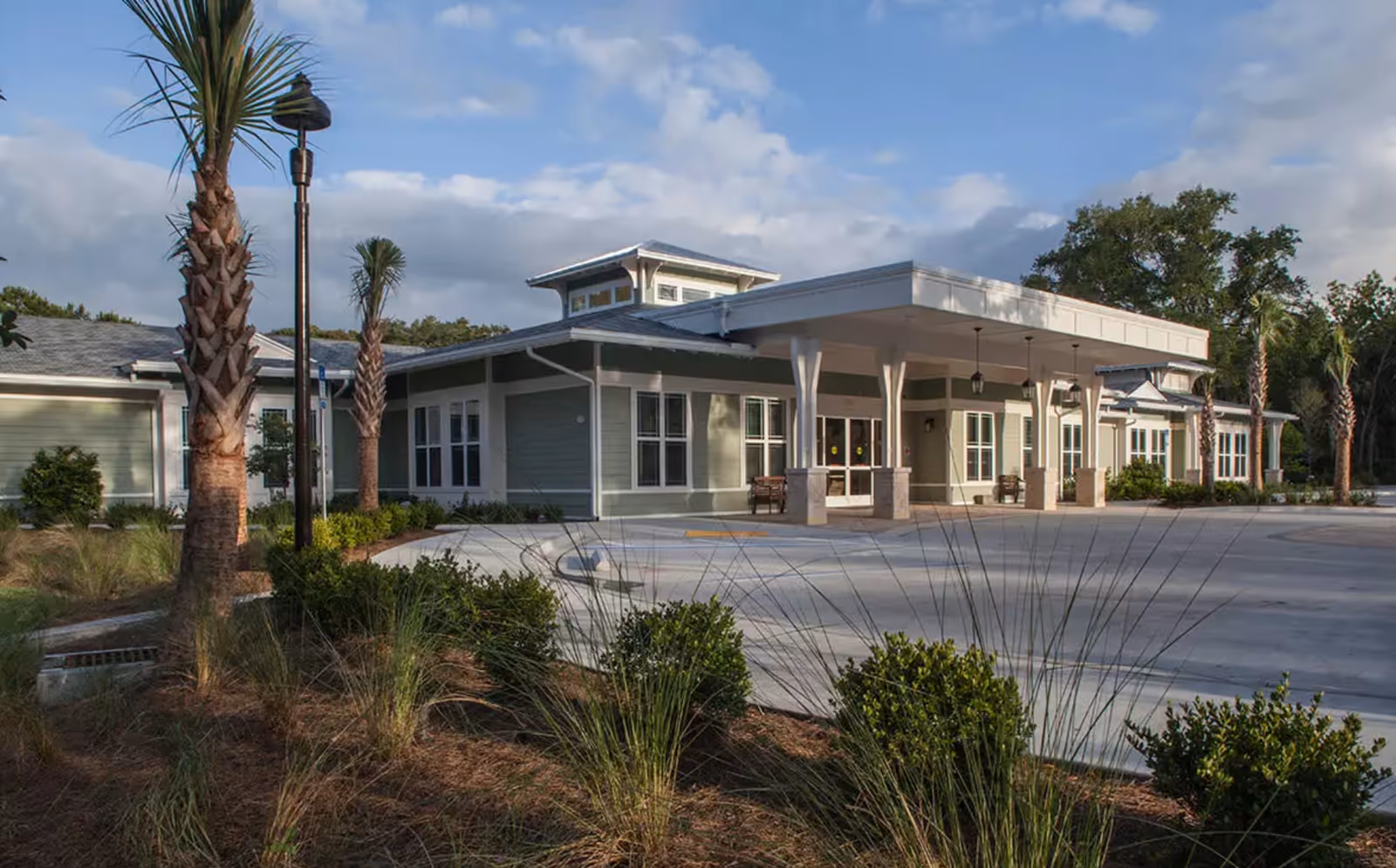 Front exterior of Mount Pleasant Gardens senior living facility with covered entrance and landscaping.