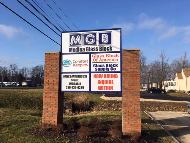 Outdoor brick sign in front of a building advertising Comfort Keepers and Medina Glass Block.